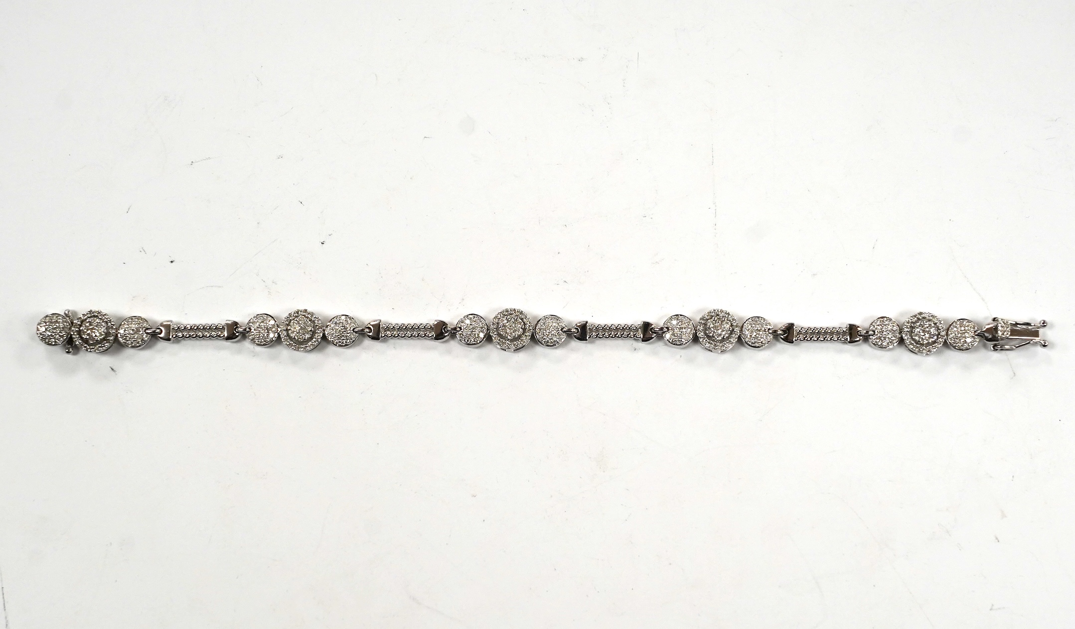 A modern 14k white metal and diamond cluster set line bracelet, the total diamond weight approximately 2.00ct, 16.5cm, gross weight 11.1 grams.